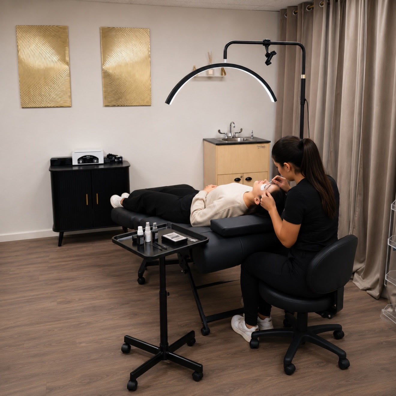An esthetician working on a client lying on the treatment bed, under the arch lamp.