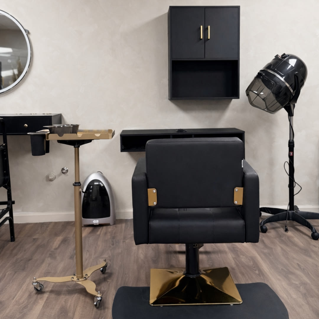 The hair station: a black styling chair on a gold base, a wall cabinet, a rolling tray and a hooded dryer.